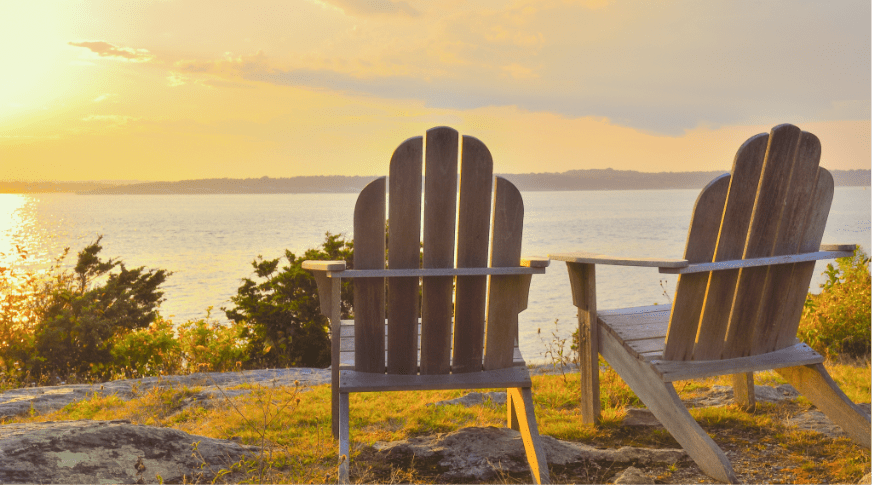 Two chairs by lake at sunset